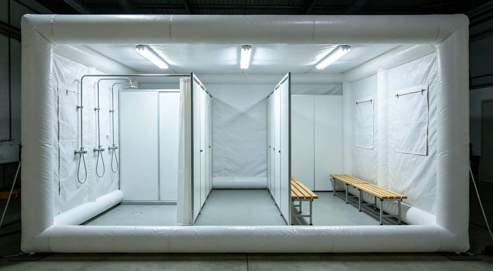 Full interior view of inflatable decontamination tent with shower area and changing space, bright lighting red and white inflatable emergency shelter for disaster relief operations