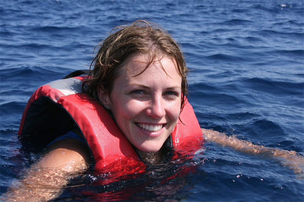 Person swimming in ocean wearing life jacket, PFD use for water safety and personal flotation device demonstration