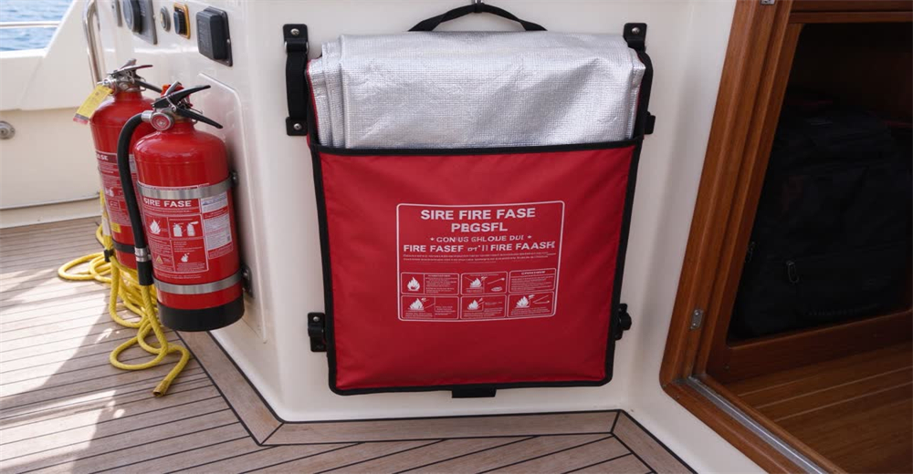 Front view of grey fire blanket mounted on galley wall showing marine fire safety equipment for boat kitchen