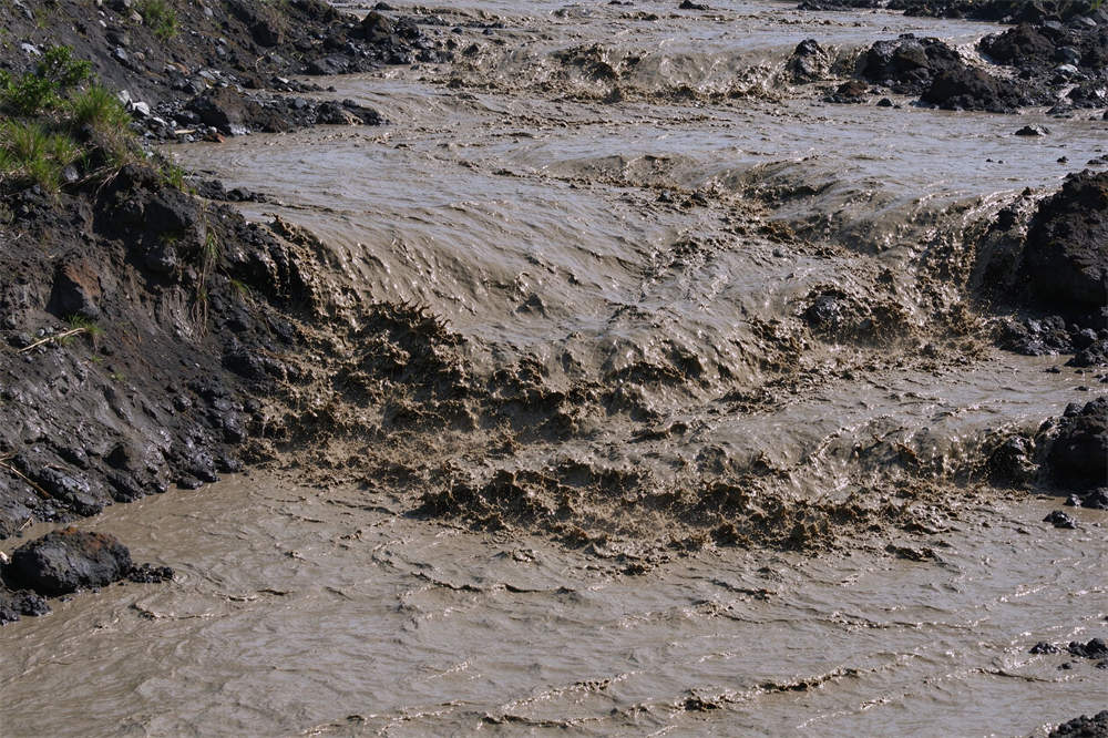 Lahar mudflow flowing through volcano terrain, volcanic hazard awareness and volcano emergency kit preparation for evacuation